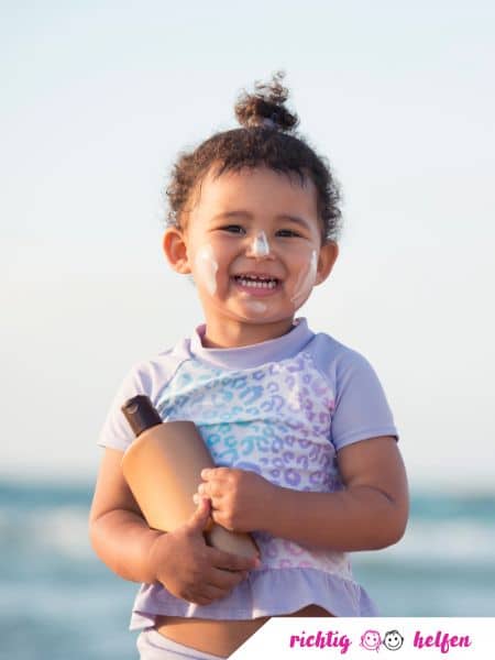 Kind mit Sonnencreme am Meer